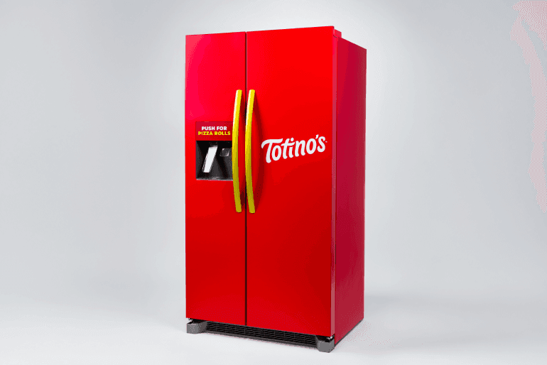 Bright red Totino's-branded refrigerator with bold yellow handles and a built-in dispenser labeled "Push for Pizza Rolls." The fridge stands against a plain white background, emphasizing its vibrant color and novelty design.
