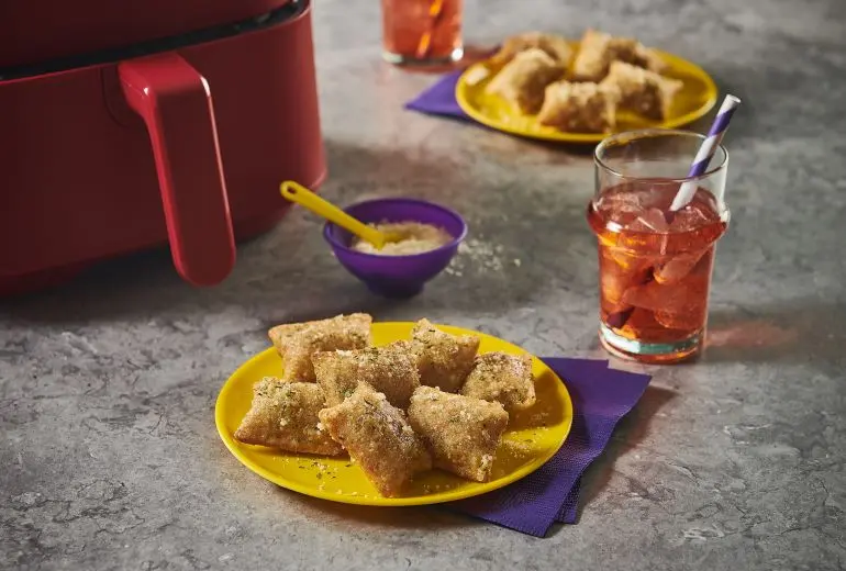 Totino's Parmesan Garlic Pizza Rolls recipe served on a yellow plate alongside iced tea. An airfryer is visible behind.